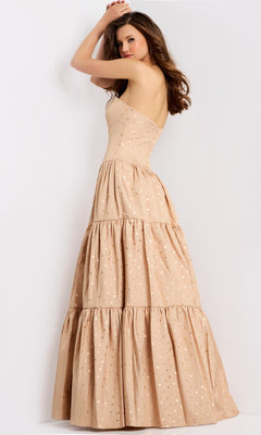 A woman poses against a plain background in the Jovani 49341 long prom dress—strapless, beige, floor-length, with a tiered skirt and subtle polka dot pattern.