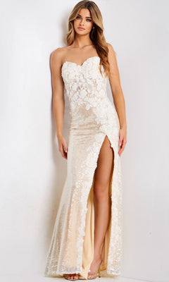A woman stands against a plain background wearing the Jovani 49362, a strapless, floor-length beige prom dress with floral lace details and a high slit.