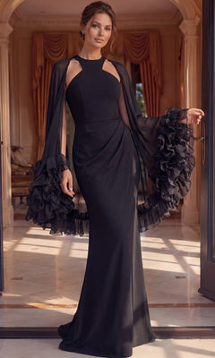 A woman stands indoors wearing an elegant Jovani 49448 long formal dress—an exquisite black, floor-length gown with draped ruffled sleeves—posing in a well-lit room adorned with ornate curtains and arched doorways in the background.