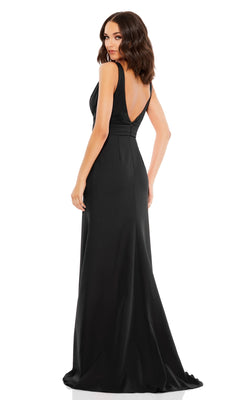 Woman in the Mac Duggal 49454 Shoulder-Bow Long Prom Dress, a sleeveless, floor-length black gown with a deep V-back, stands looking over her shoulder.