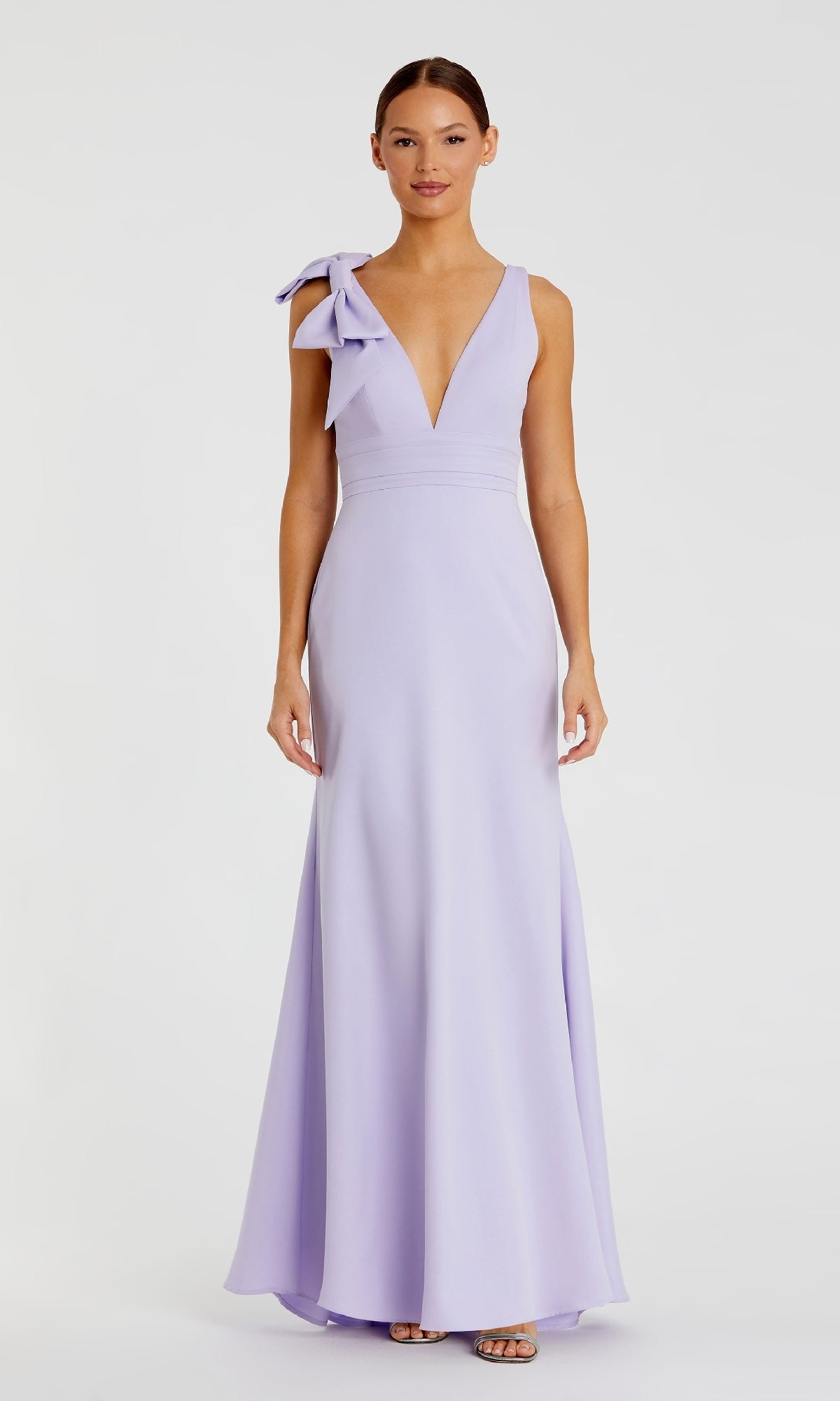 A woman models the Mac Duggal 49454 Shoulder-Bow Long Prom Dress in lavender, featuring a deep V-neckline, large shoulder bow, and elegant A-line silhouette, posed against a plain white background.