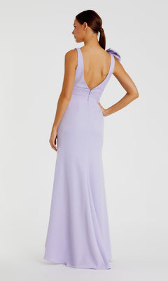 A woman faces away from the camera in the Mac Duggal 49454 Shoulder-Bow Long Prom Dress, a light purple A-line gown featuring a deep V-back and bow detail on one shoulder, set against a plain background.