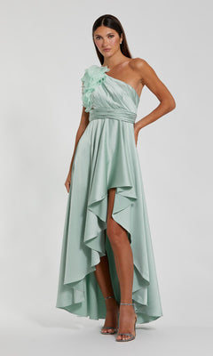 A woman models the Mac Duggal 49523 one-shoulder wedding guest dress in light green, featuring a high-low hem and floral ruffle detail, paired with strappy heels—a perfect party outfit.