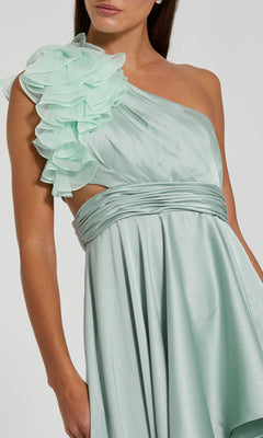 Woman wearing the Mac Duggal 49523 One-Shoulder Wedding Guest Dress in light green, featuring a ruffled one-shoulder detail and a pleated waistband.