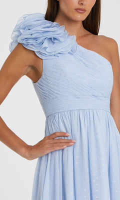 A woman wears the Mac Duggal 49536, a light blue one-shoulder long formal dress featuring pleated fabric and a large ruffled shoulder detail.