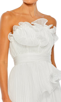 A woman wearing the Long Formal Dress 49537 by Mac Duggal, a strapless formal gown featuring an empire waist, pleated white fabric, and ruffled detailing on the bodice and waist.
