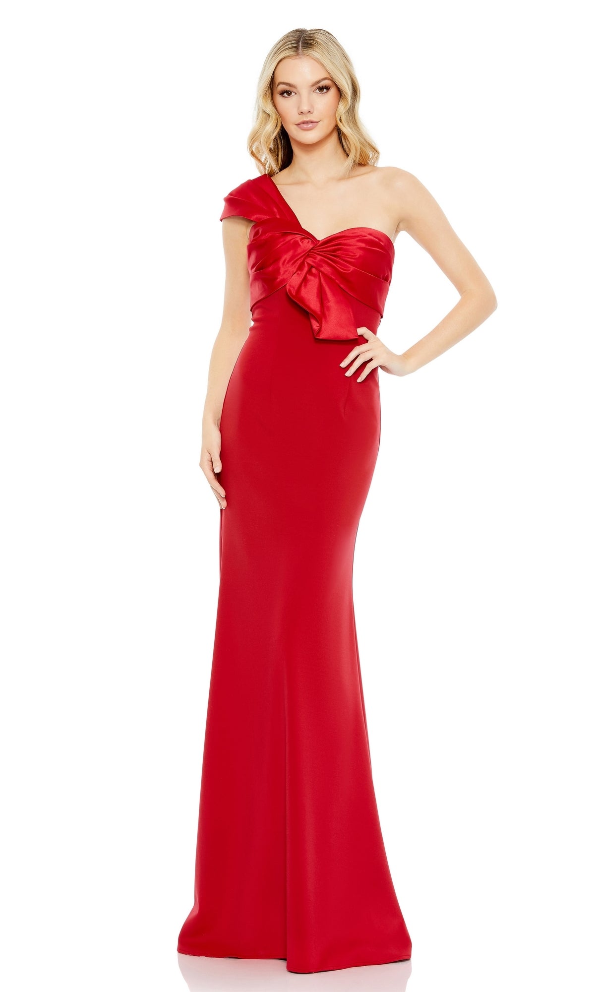 A woman wearing the Mac Duggal One-Shoulder Long Bow Prom Dress 49547 in floor-length red, featuring a large bow on the bodice, stands against a plain white background.