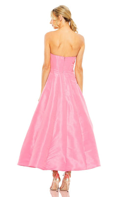 A woman faces away, wearing the Mac Duggal 49605 tea-length wedding-guest dress in pink with a strapless fitted bodice and flared skirt, paired with pink platform heels.