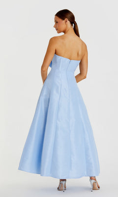 A woman in the Mac Duggal 49605 tea-length wedding-guest dress and silver high heels stands facing away from the camera against a plain background.