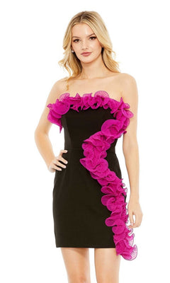A woman wears the Short Homecoming Dress 49642 by Mac Duggal—a strapless black party dress with bright pink ruffle detail across the neckline and front—posing against a plain white background.