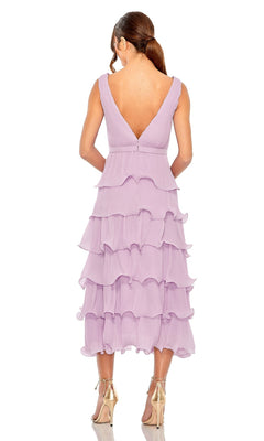A woman stands with her back to the camera, wearing the Mac Duggal 49671 Midi Wedding Guest Dress—sleeveless, tea-length purple chiffon with tiered ruffles—paired with metallic high-heeled shoes.
