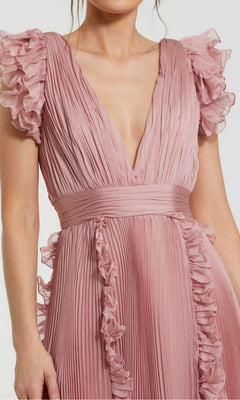 A person wearing the Short Wedding Guest Dress 49675 by Mac Duggal in rose pink chiffon, featuring pleated details, ruffle cap sleeves, and a deep V-neckline.
