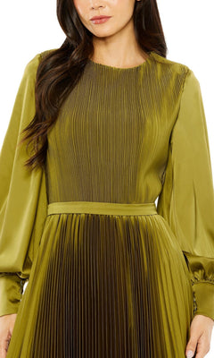 A woman wearing the Tea Length Formal Dress 49718 by Mac Duggal—an olive green, long sleeve dress with vertical pleats on the bodice and skirt—shown from mid-thigh up.