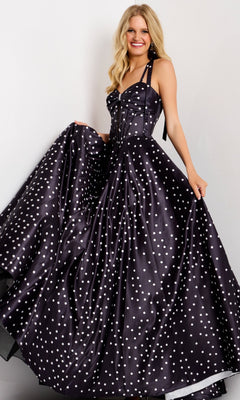 A woman smiles in the Jovani 49774 Long Prom Dress in black, featuring a polka-dot satin fabric, halter neckline, and flowing A-line skirt as she holds out the sides against a plain background.