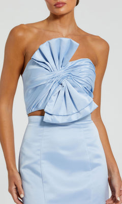 A person wears the Strapless Two-Piece Prom Gown: Mac Duggal 49832, featuring a light blue satin top with sculptural ruffle detail and a matching high-waisted mermaid skirt for an elegant, coordinated long prom dress look.