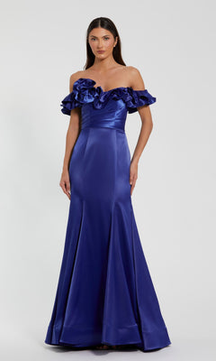 A woman stands against a plain background, wearing the Mac Duggal 49834 Ruffled Long Satin Prom Dress—an off-the-shoulder, royal blue gown with a floor-length skirt and ruffled neckline.