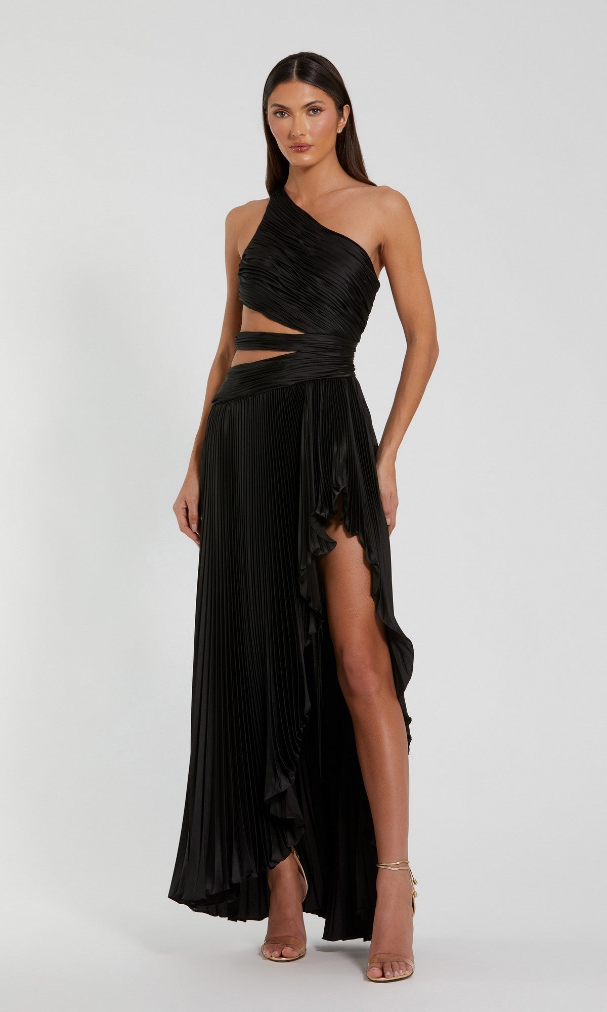 A woman wearing the Mac Duggal 49837 High-Low Pleated Formal Dress with a one-shoulder cut-out and high slit, posed against a plain light background.
