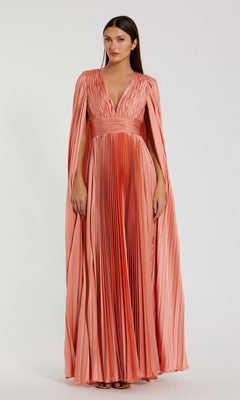 A woman stands against a plain background wearing the Mac Duggal 49872 Cape-Sleeve Long Formal Dress, a floor-length peach gown with pleats, cape-style sleeves, and a deep V-neckline.