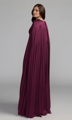 A woman in profile wears the Mac Duggal 49872 Cape-Sleeve Long Formal Dress in deep purple, featuring pleats and a cape-style design, set against a plain light gray background.