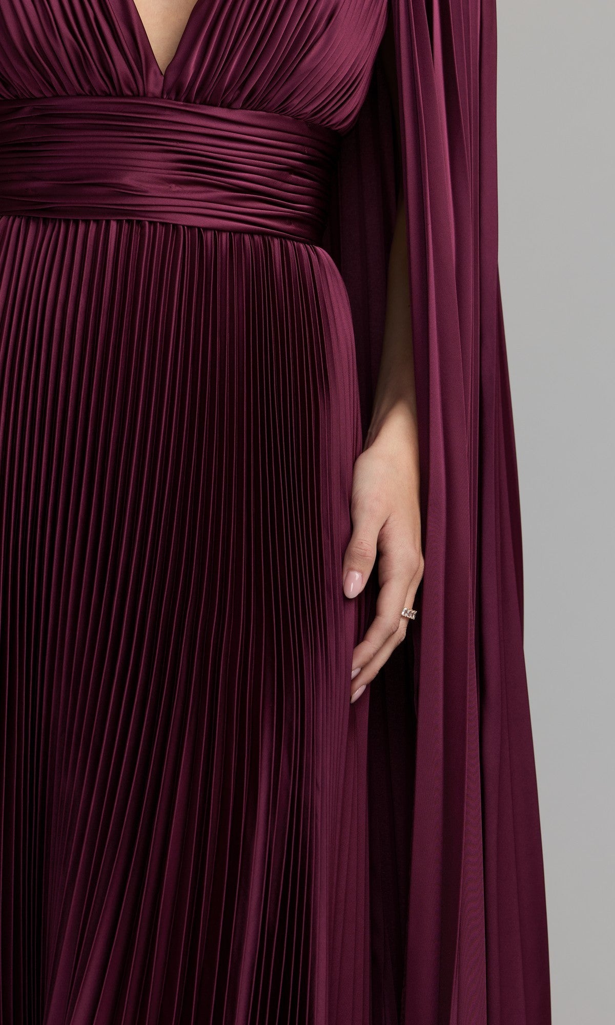 A person wearing a deep burgundy Mac Duggal 49872 cape-sleeve long formal dress with a deep V neckline, shown from shoulders to hips, with one hand resting by their side.