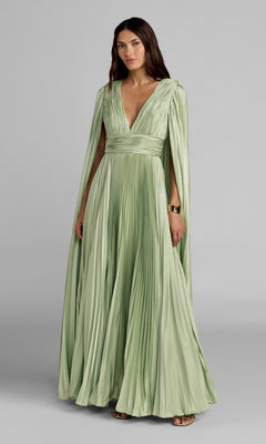 Model wears the Mac Duggal 49872 Cape-Sleeve Long Formal Dress—floor-length, pale green with pleats, a deep V-neckline, long draped cape sleeves, and a gold bracelet—posing against a plain gray background.