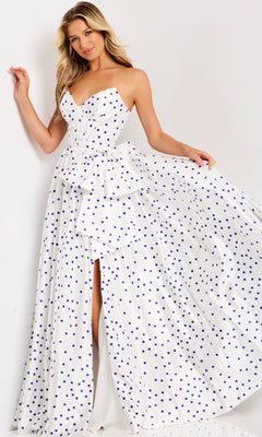 A woman stands against a plain background wearing the Jovani 49899, a long strapless polka dot prom dress with a peplum waist and thigh-high slit.
