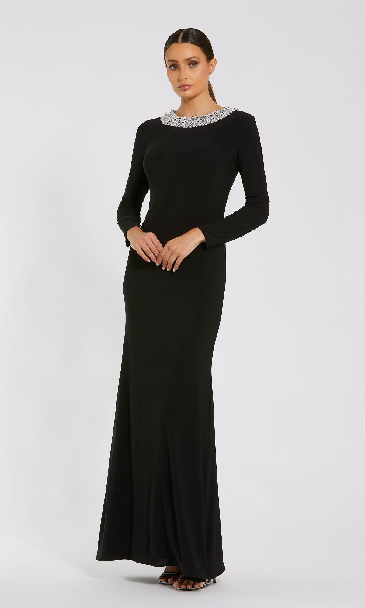 A woman wearing the Mac Duggal 49951 long sleeve black formal dress stands against a plain white background.