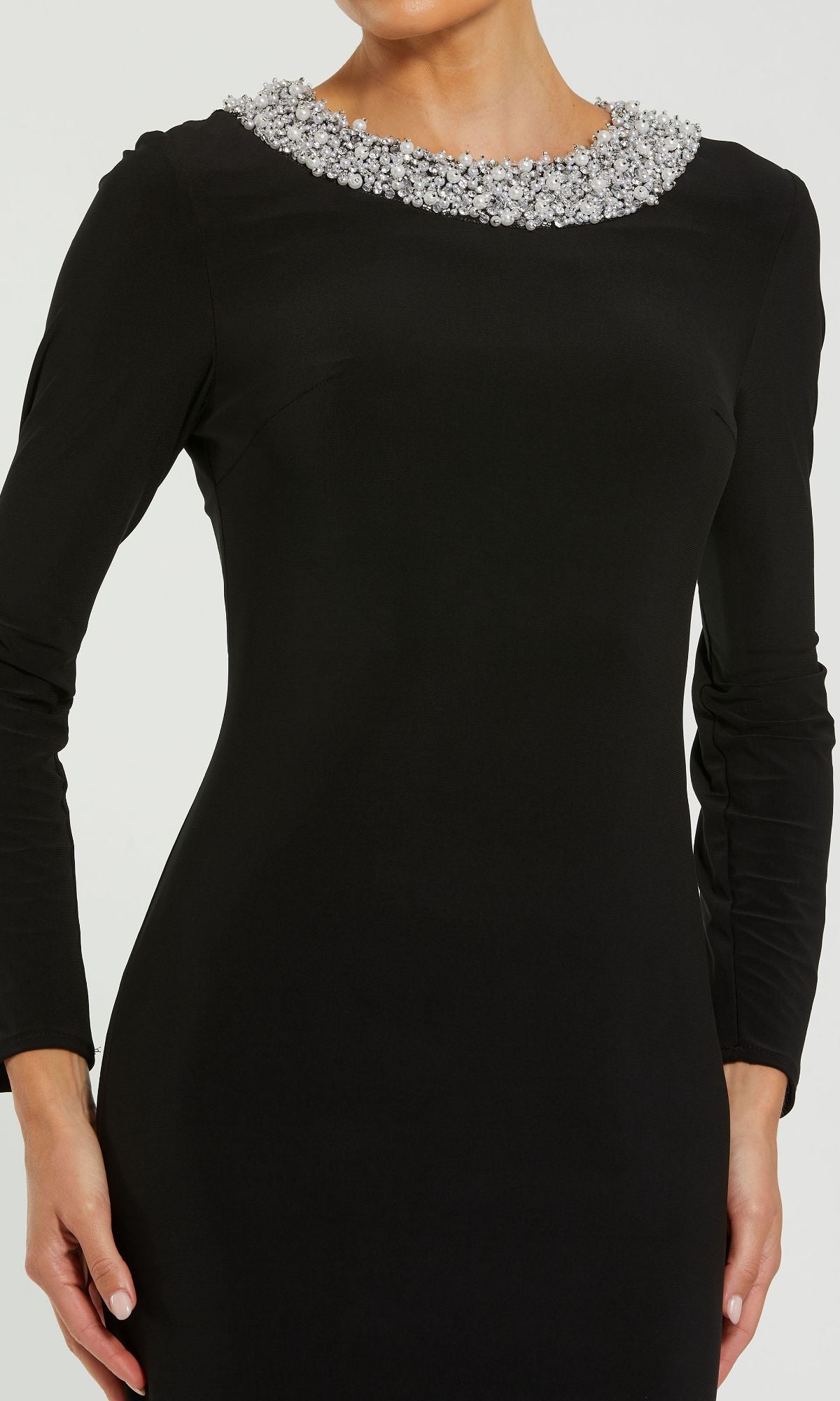 A woman wears the Long Sleeve Black Formal Dress: Mac Duggal 49951, a fitted black gown with long sleeves and silver beaded round neckline, ideal for formal evening events.