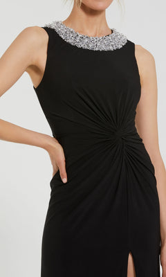 A woman wears the Jeweled Long Black Formal Dress (Mac Duggal 49952), featuring a sleeveless design, jeweled neckline, and gathered waist detailing.