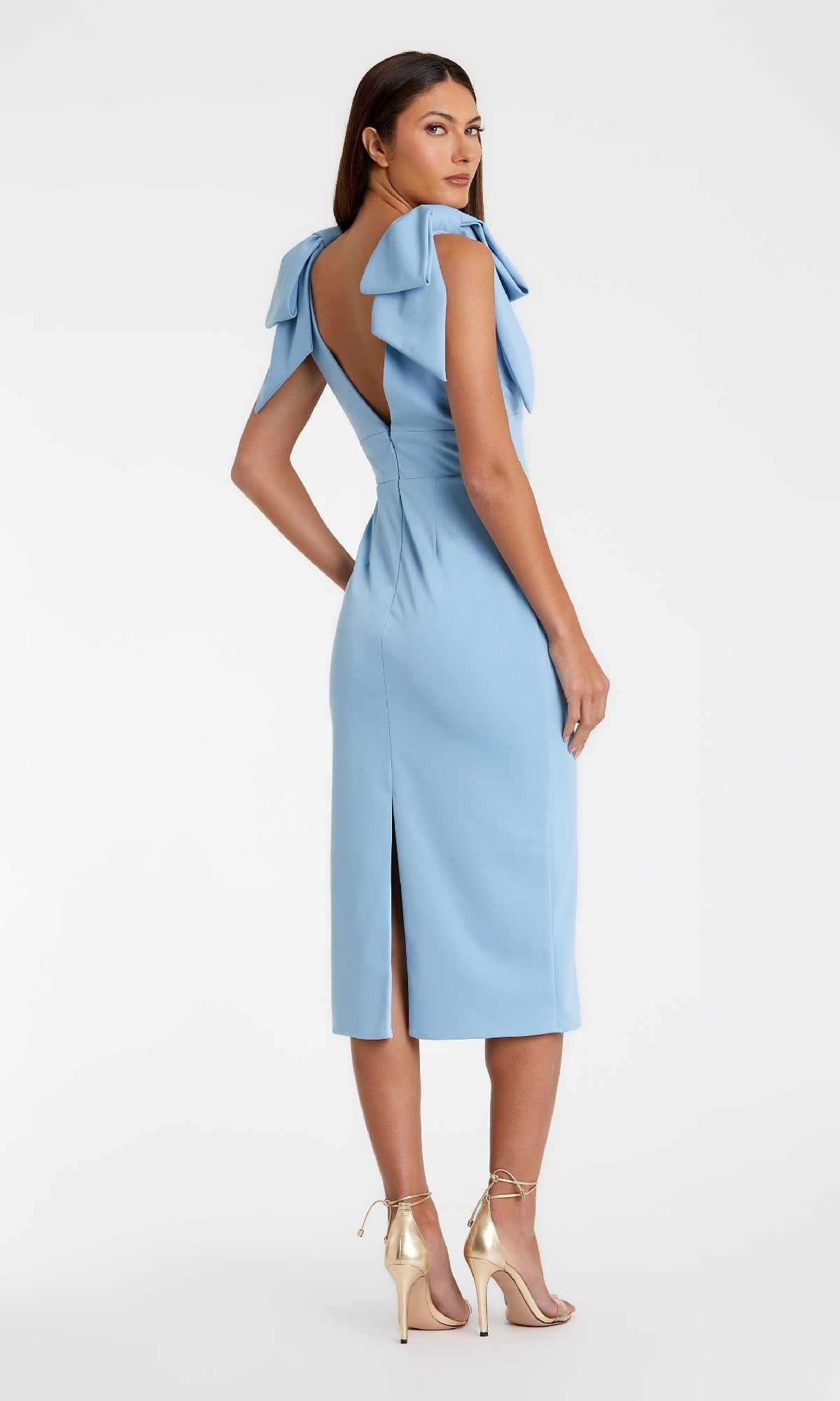 A woman models the Mac Duggal 49954 V-Neck Midi Wedding Guest Dress featuring ruffle shoulder details and a deep V-back, paired with gold high-heeled sandals against a plain background.