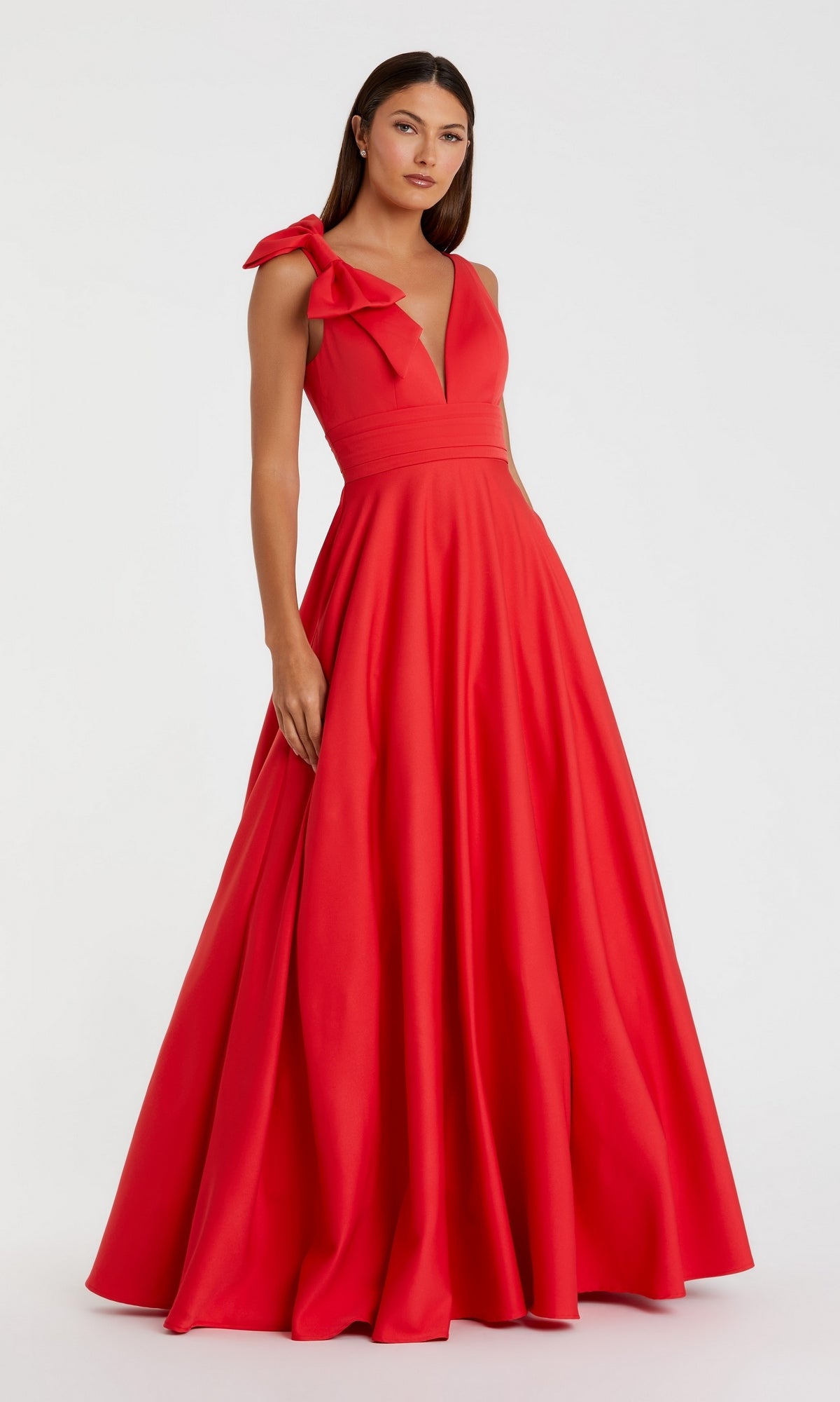 A woman stands against a plain white background wearing the Shoulder-Bow Long Formal Dress: Mac Duggal 49972, a red sleeveless gown with a deep V neckline and an oversized bow accent on one shoulder.
