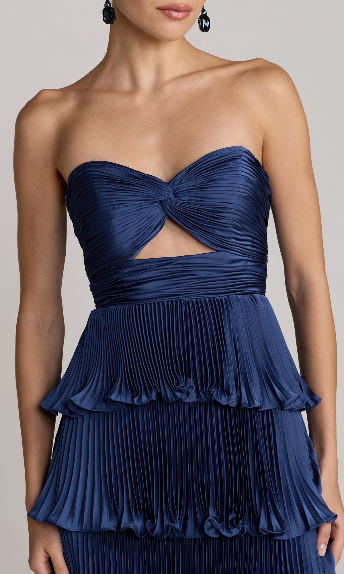 A woman wearing the Mac Duggal 49981 Strapless Pleated Long Formal Dress in navy blue, featuring a knotted bodice and keyhole cutout at the chest—a stunning choice for any special occasion.