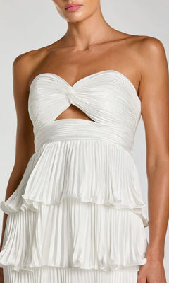 Woman wearing the Mac Duggal 49981 long formal dress, a strapless white gown with a knotted bodice, small front cutout, and layered pleated skirt.