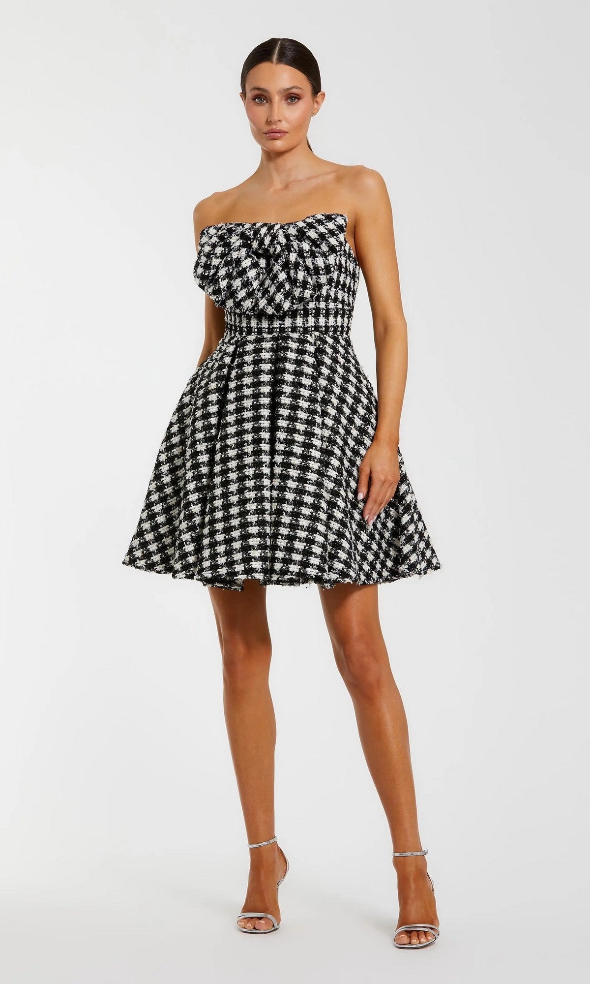 A woman in a black ivory strapless houndstooth Mac Duggal 50027 dress with a fitted waist and flared skirt, paired with silver heels—an elegant pick for any semi-formal event.