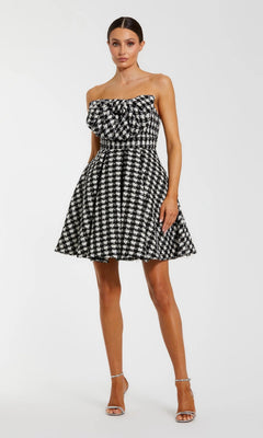 A woman in a black ivory strapless houndstooth Mac Duggal 50027 dress with a fitted waist and flared skirt, paired with silver heels—an elegant pick for any semi-formal event.