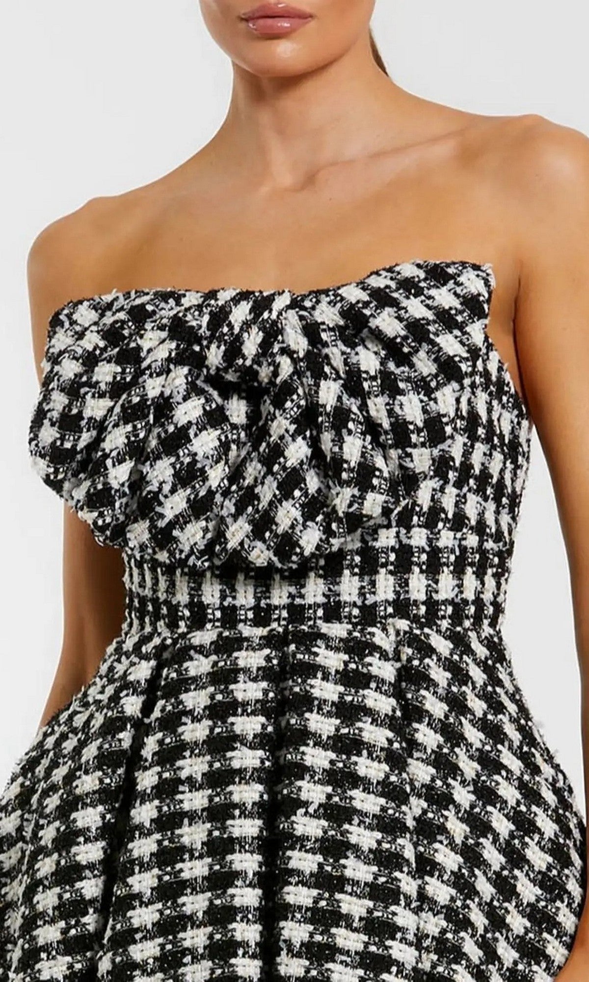 A woman wears the Mac Duggal 50027, a short semi-formal dress featuring a strapless houndstooth design and bold ruffle detail for a chic look.