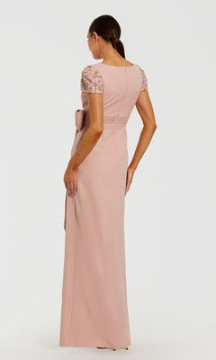 A woman in a floor-length, green Mac Duggal 50054 formal gown with short sleeves stands facing away, highlighting the elegant back of this stunning evening dress.