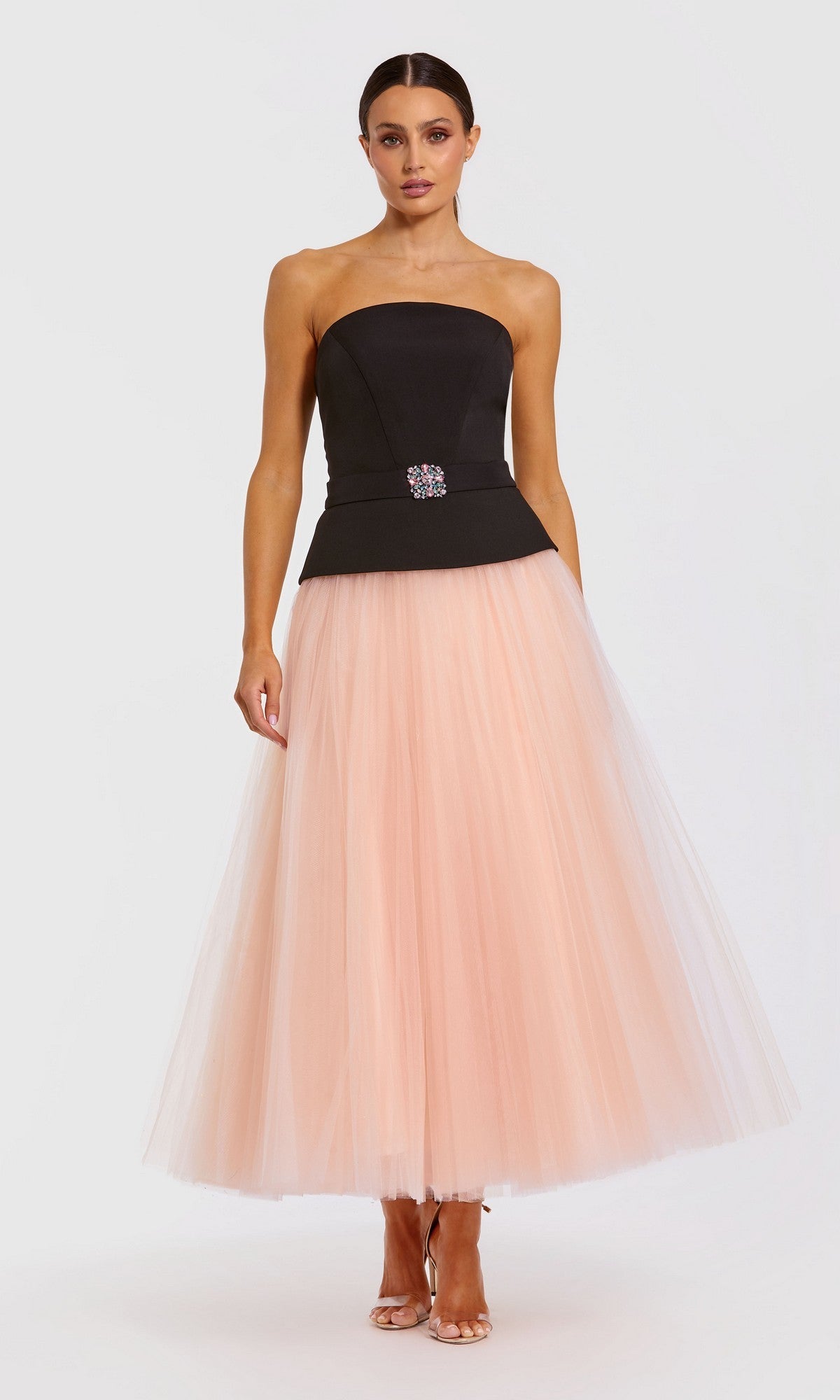 A woman stands against a plain white background wearing the Long Formal Dress: Mac Duggal 50063 in Black Pink—a strapless, tea-length dress with a jeweled black bodice and a full pink tulle midi skirt.
