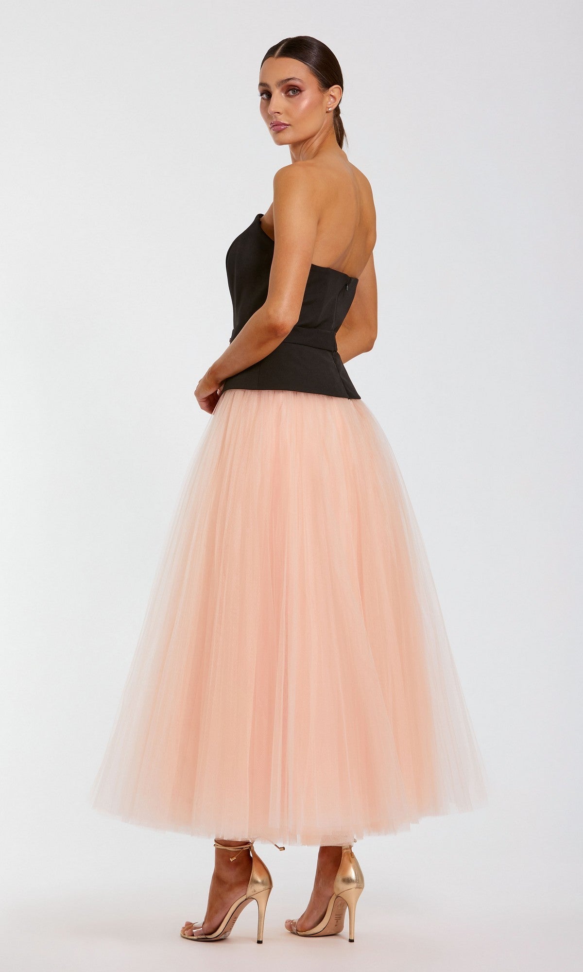 A woman stands in profile with a neutral expression against a plain light background, wearing the Mac Duggal 50063 long formal dress.