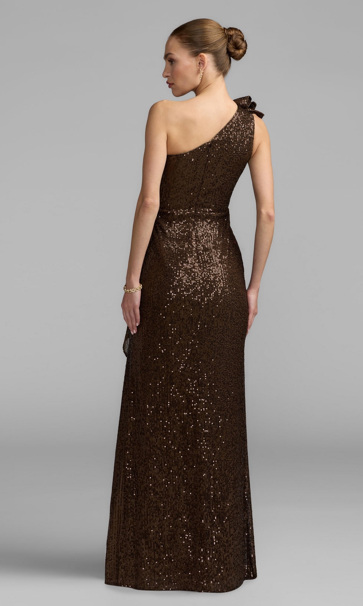 A woman stands with her back to the camera against a plain gray background, wearing the floor-length Long Blue Sequin Formal Gown by Mac Duggal (style 50093), featuring a one-shoulder design.
