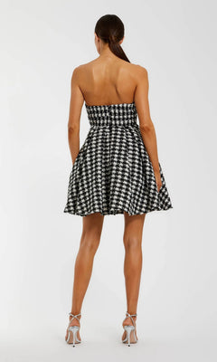 Woman seen from behind in a Mac Duggal 50027 strapless houndstooth short semi-formal dress with white high-heeled sandals, set against a plain background for a chic look.