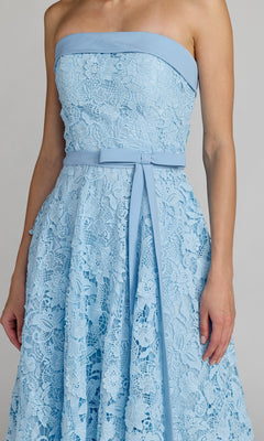 A person wearing the Mac Duggal 50114 Tea-Length Party Dress—a strapless, light blue floral embroidery lace dress with a matching belt—photographed from the shoulders to the knees. The elegant look highlights the timeless charm of this classic tea-length party dress.