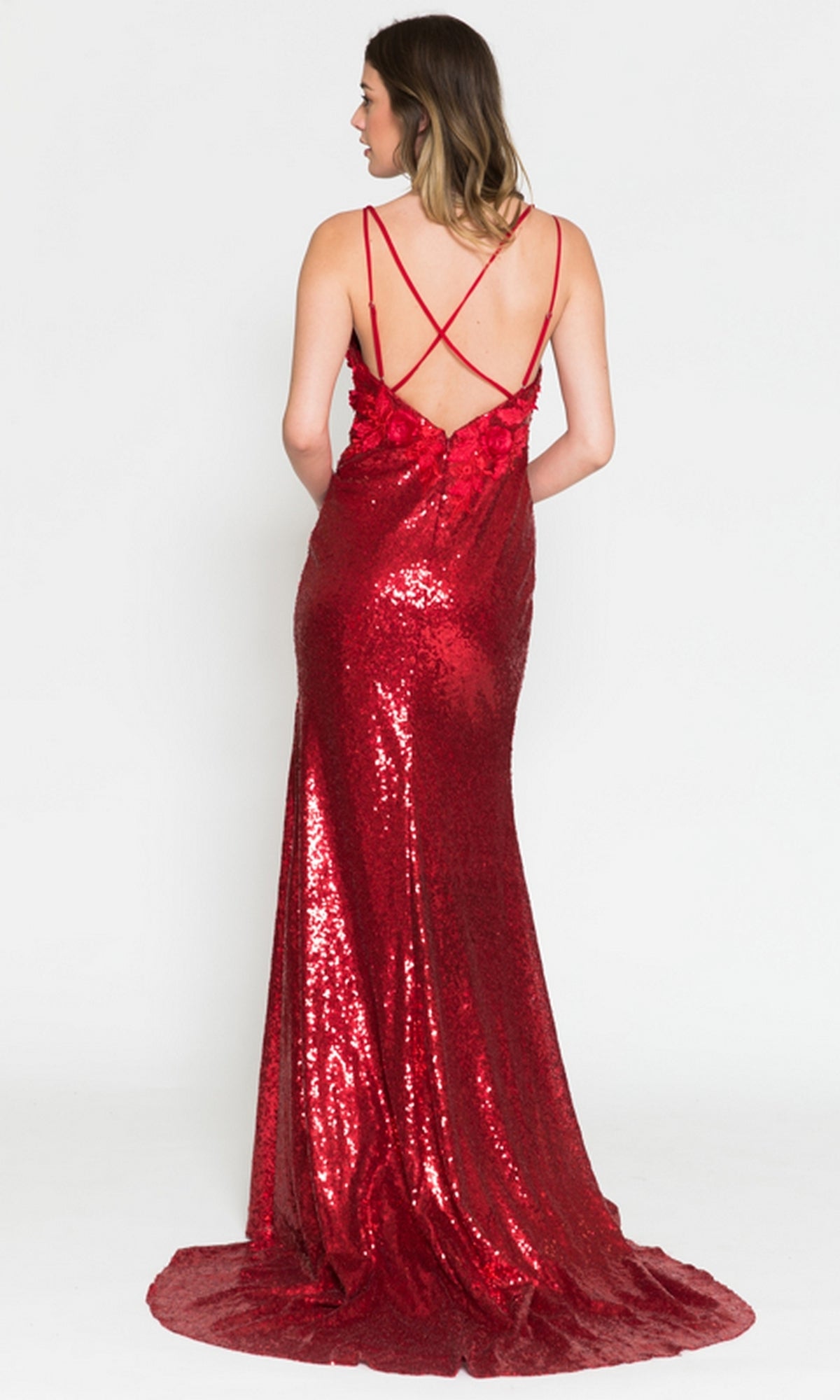 A woman faces away, wearing a Floral-Embellished Long Sequin Prom Dress 5020 with a floor-length red sequin design, low back, and crisscrossed thin straps.