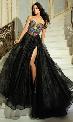 A woman stands on a staircase wearing the Long Prom Dress Jovani 50255 in Black/Multi, featuring a strapless beaded corset bodice and a full black organza skirt with a high slit.