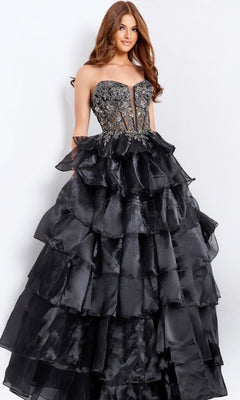 A woman in the Jovani 50259 long prom dress stands against a plain light background, showcasing its strapless black design with an embroidered corset bodice and a tiered, ruffled skirt.