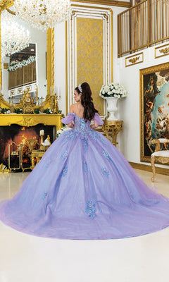 A young woman wears the Quinceanera Dress 5039 By Dancing Queen, featuring a lilac glitter tulle skirt, as she stands facing away in an ornate gold-accented room with a fireplace and classical decor.