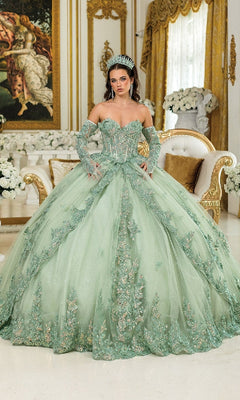 A woman in the Green Quinceanera Dress 5047 By Dancing Queen, featuring a corset bodice and floral details, stands in a lavish room with gold-accented furniture and white floral arrangements.
