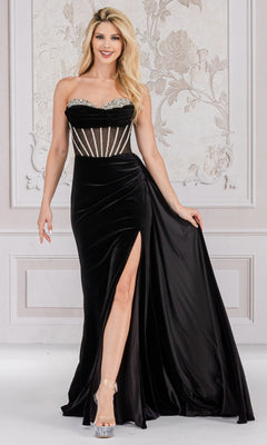 A woman wearing the Sheer-Waist Strapless Long Velvet Prom Dress 5051, featuring a sheer striped bodice and thigh-high slit, stands before a decorated wall.