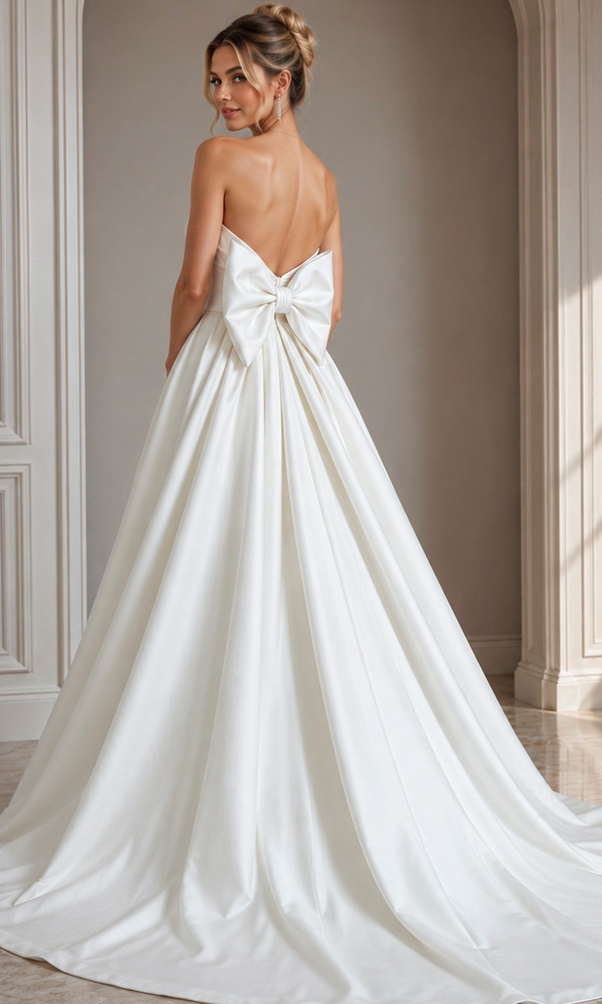 A woman in a strapless satin gown with a dramatic back bow stands in an elegant room, facing away from the camera—a graceful showcase of designer formal dress style, embodied by the Long Formal Dress: Jovani 50534.