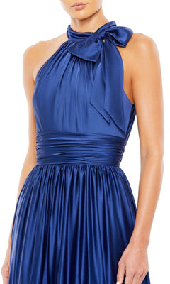 A woman wears the Mac Duggal High-Neck Satin Formal Dress 506581, a sleeveless blue halter style featuring a bow at the high neck and a fitted waistband.